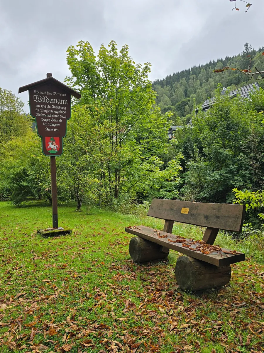 Holzbank und Schild in einem grünen Park