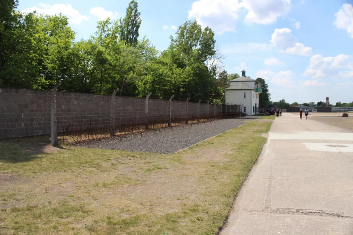 Mauer mit Stacheldraht und Gebäude im Hintergrund