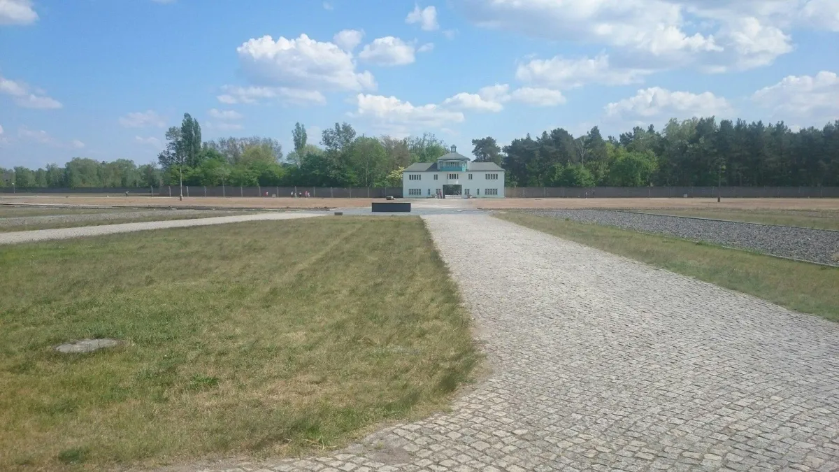 Gepflasterter Weg zu einem Gebäude in einer offenen Landschaft.