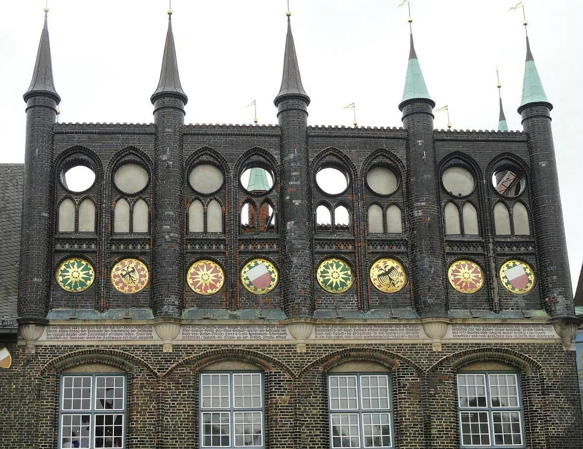 Historische Fassade mit Türmen und Wappen.
