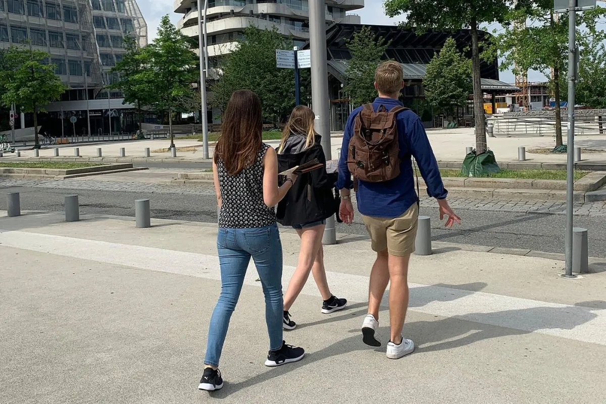 Drei Personen gehen auf einem Bürgersteig.