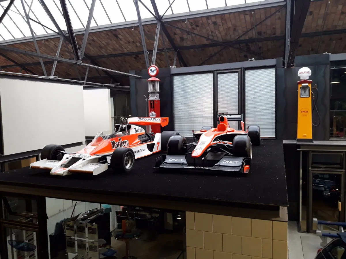 Zwei Rennwagen in einem Ausstellungsraum.