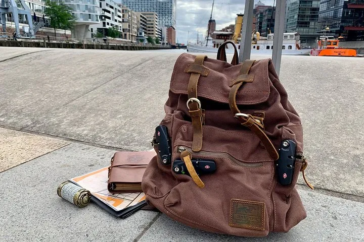 Brauner Rucksack mit Notizbuch und Karte auf dem Boden.