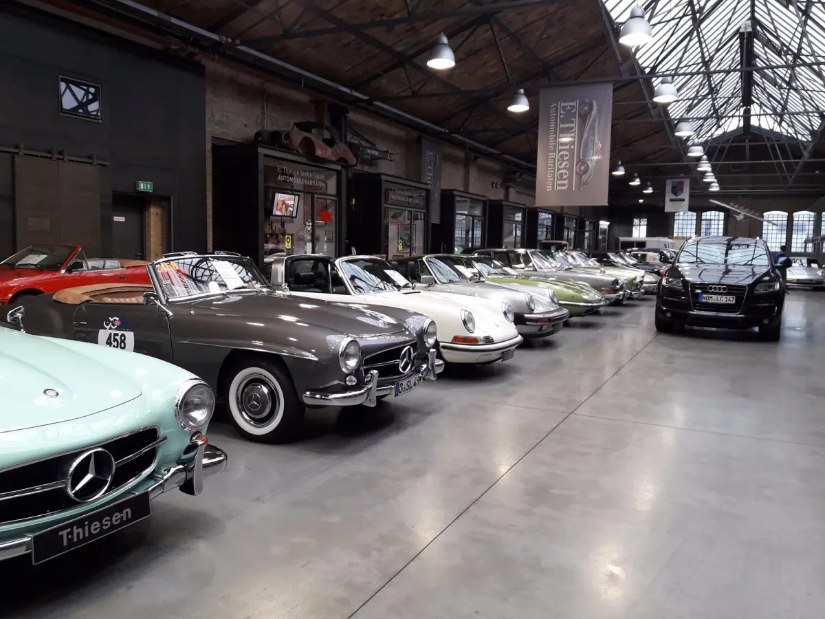 Reihe von Oldtimern in einer Ausstellungshalle.