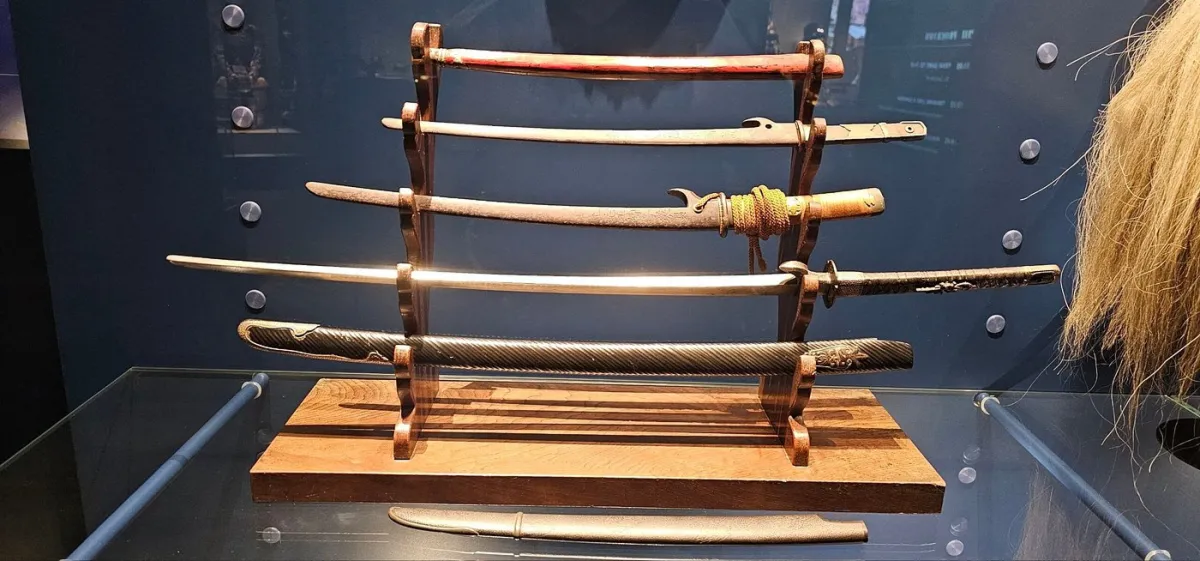 Ausstellung von fünf Schwertern auf einem Holzständer.