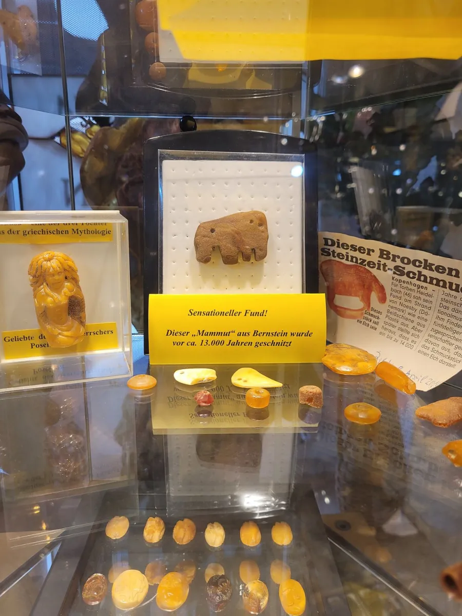 Bernsteinfiguren und Infotafel in einer Vitrine.
