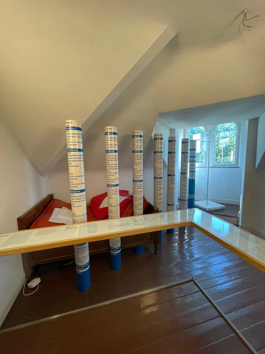Zimmer mit Informationssäulen und Bett.