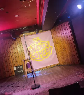 Empty comedy stage with microphone and stool.