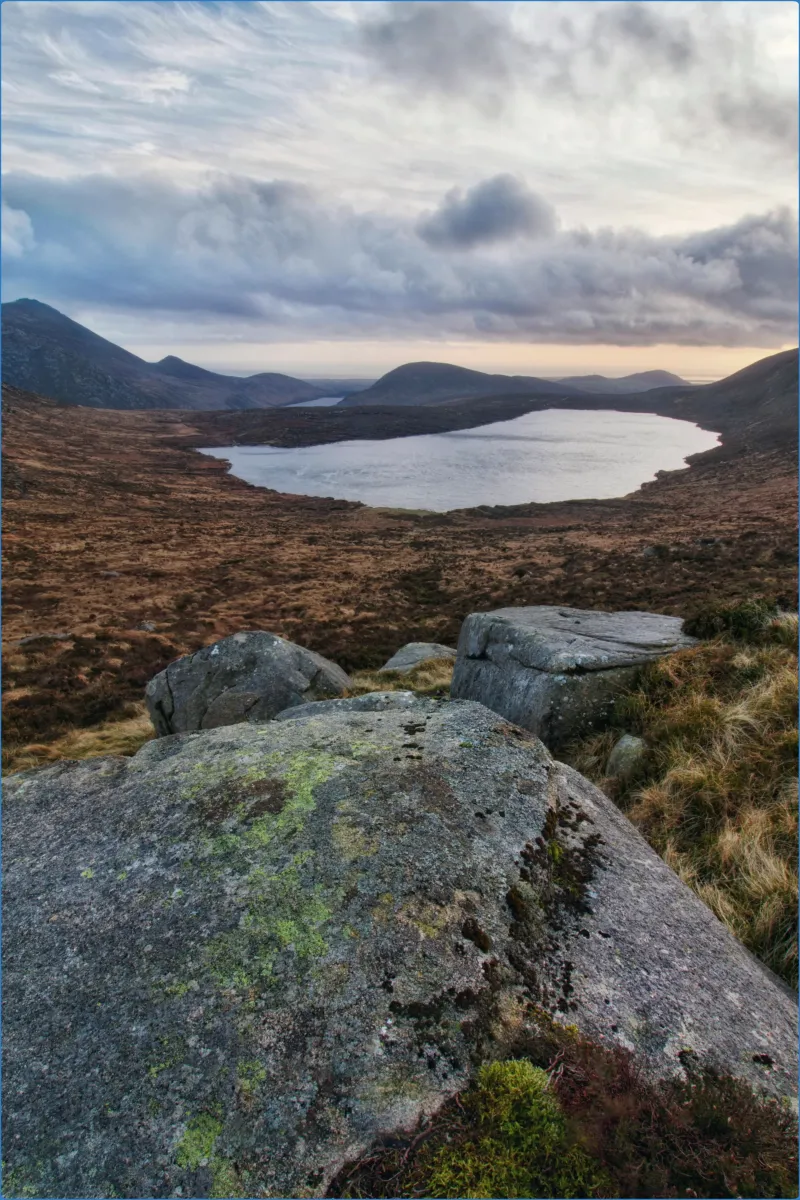 Scenic view of a lake surrounded by hills and rocks.