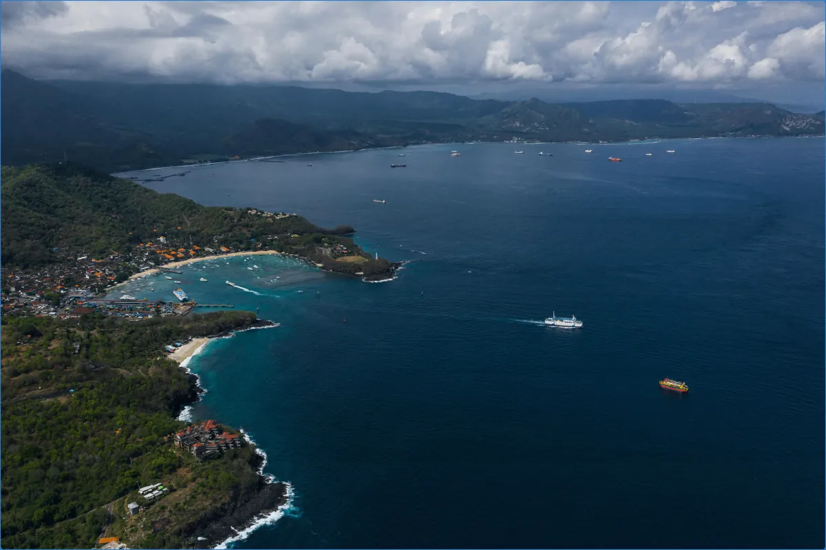 Aerial view of a coastal area with boats and mountains.