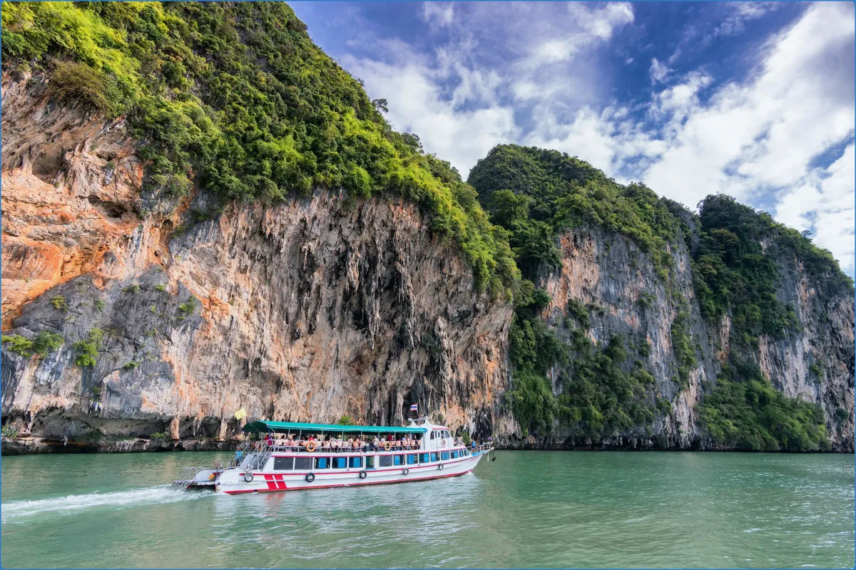Tour boat near limestone cliffs and green water