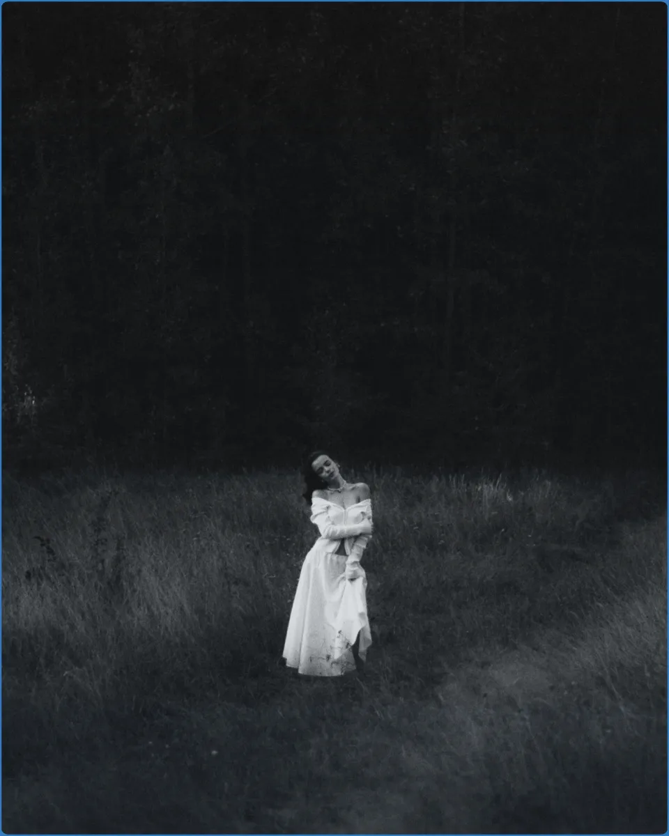 Woman in white dress standing in a dark field