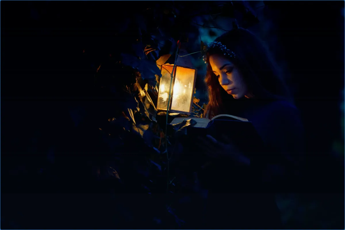 Woman reading by lantern light in a dark forest.