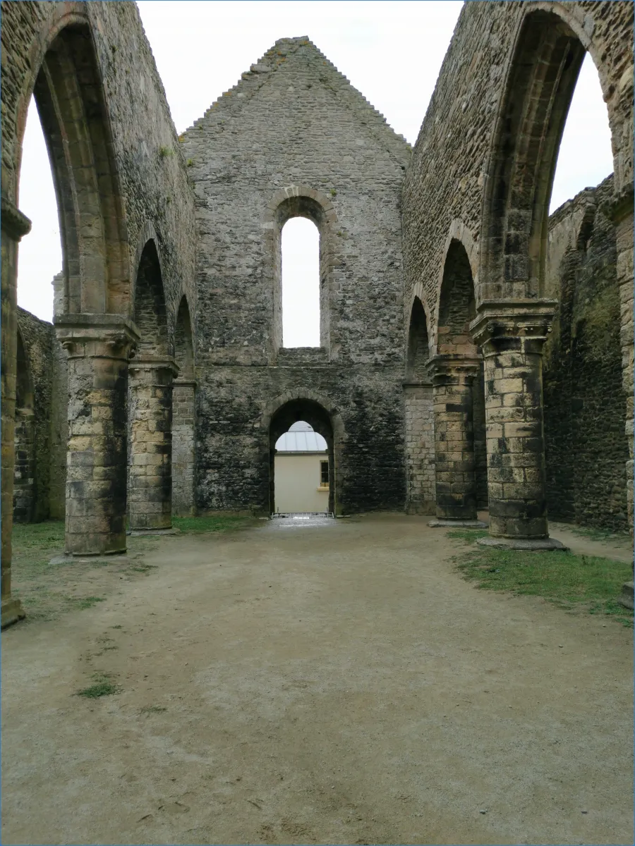 Interior of a stone ruin with arches and pillars.