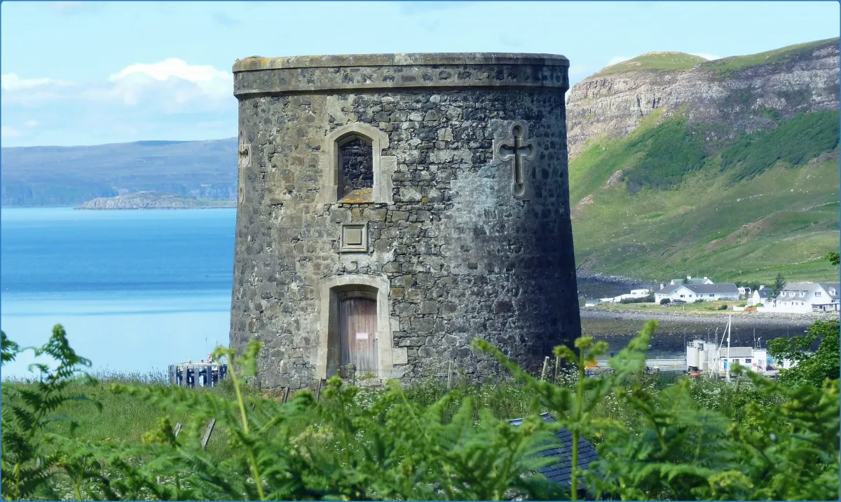 Stone tower with cross near a coastal village.