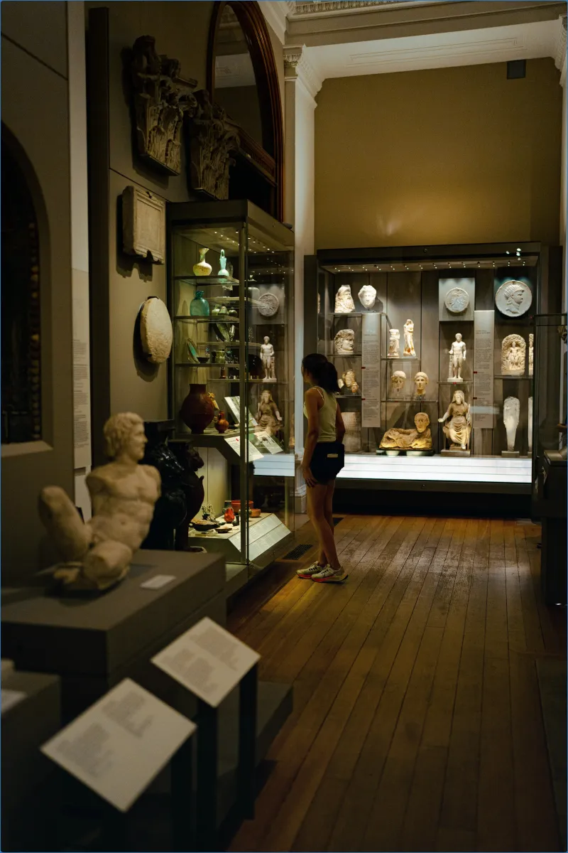 Person viewing sculptures in a museum gallery.