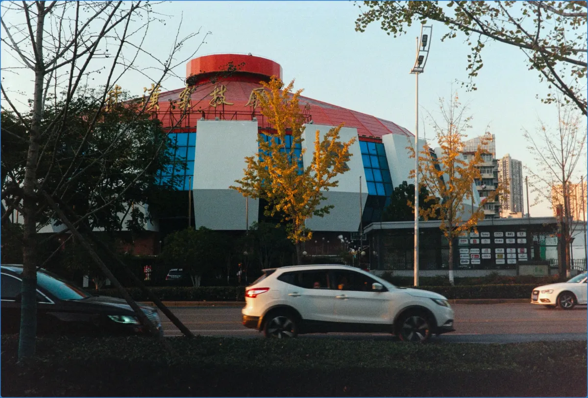 Cars passing by a modern building with a red dome