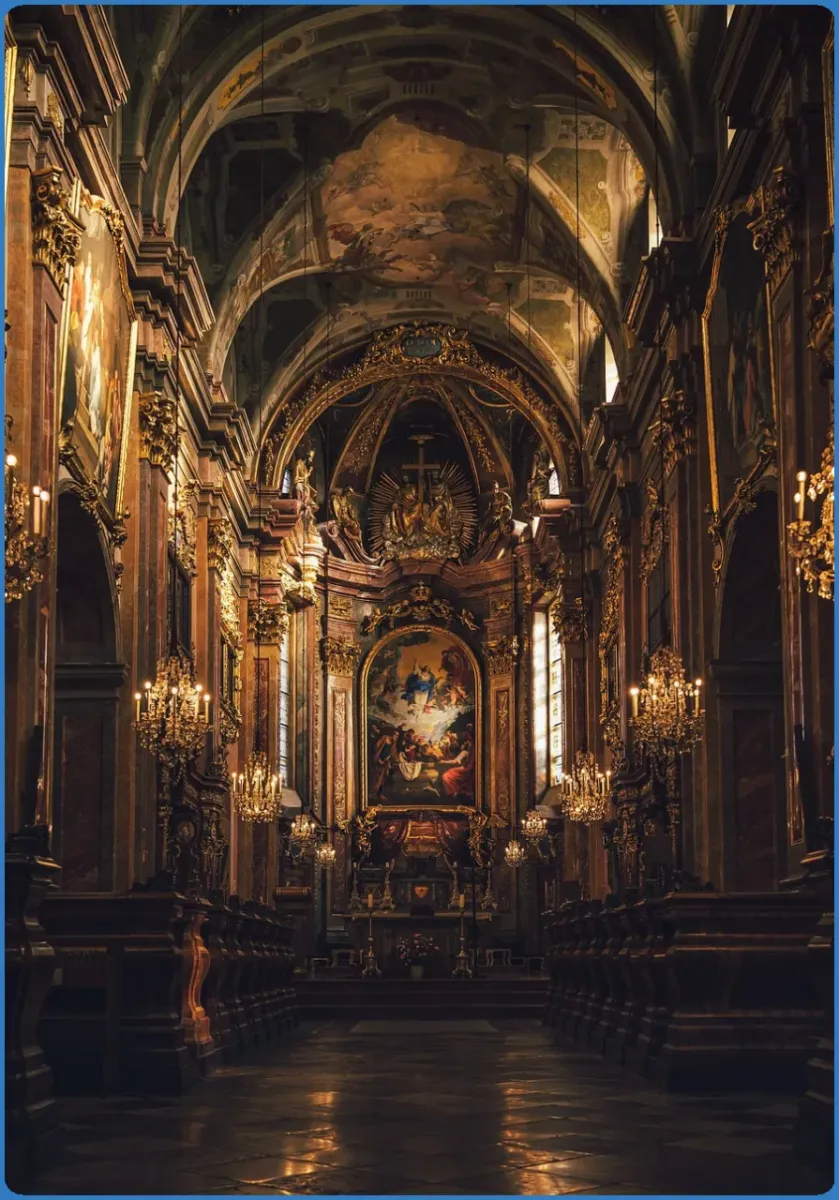 Interior of an ornate church with chandeliers and paintings.
