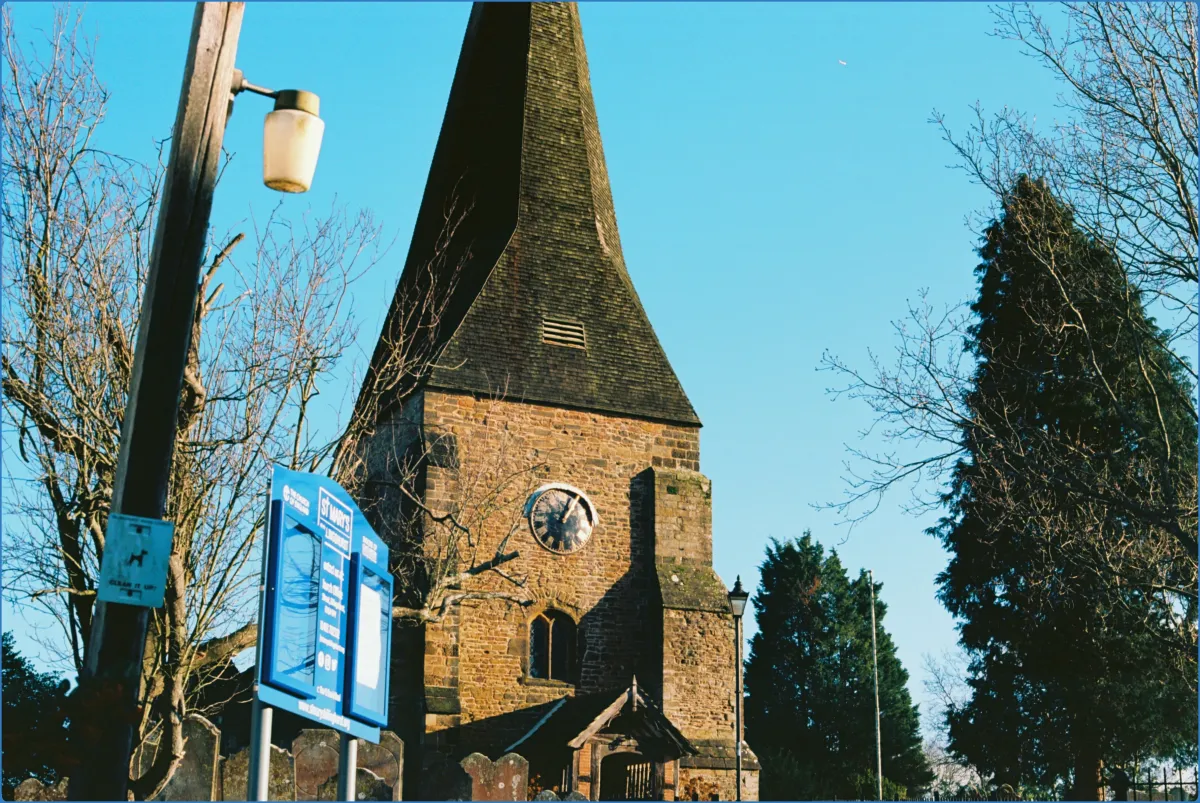 Stone church with clock tower and trees