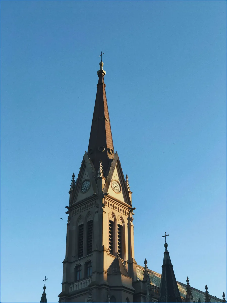 Church steeple with clock against blue sky