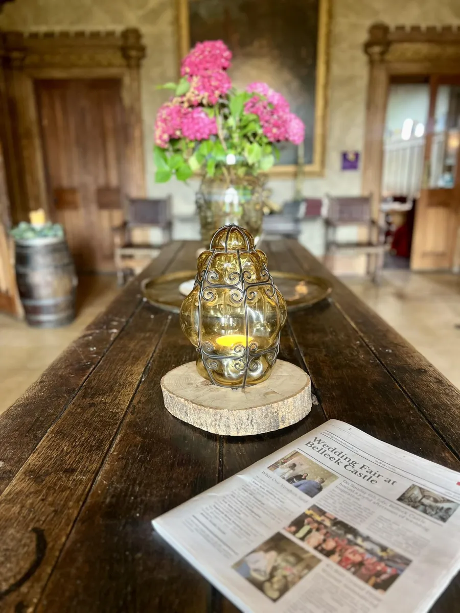 Table with a candle holder, flowers, and a newspaper.