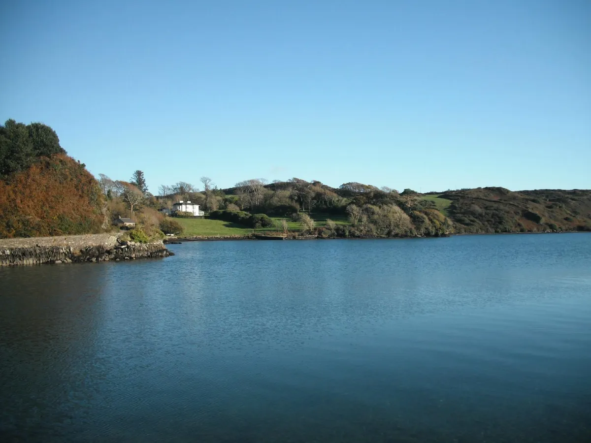 Scenic view of a lake with hills and a house.