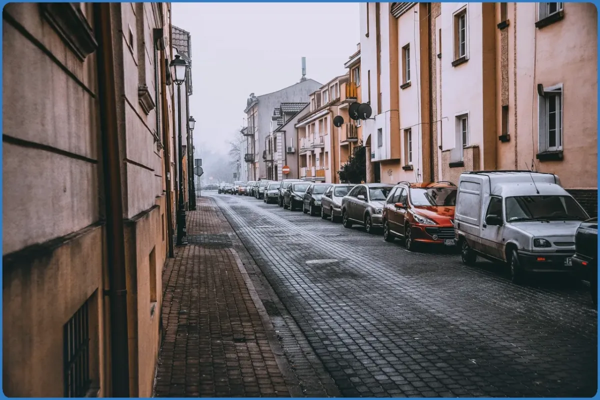 Narrow street with parked cars and buildings