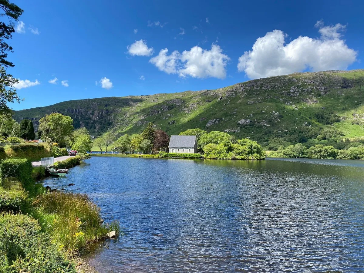 Scenic lake with mountains and a small building.
