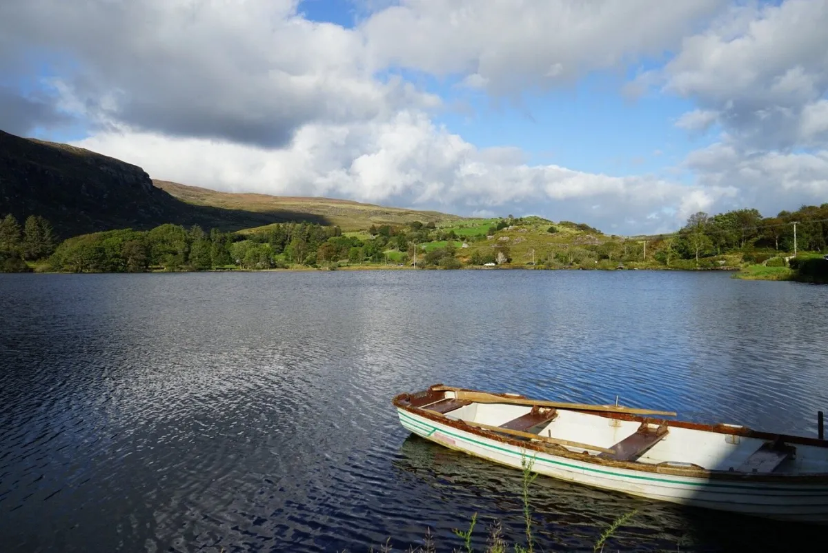 Rowboat on a calm lake with hills in the background.