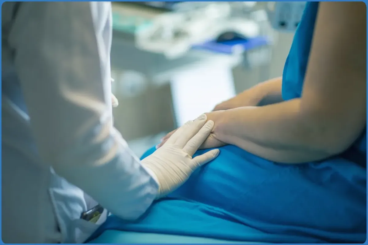 Doctor comforting patient with gloved hand.