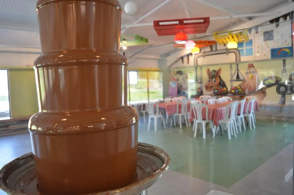 Chocolate fountain in a decorated room with tables.