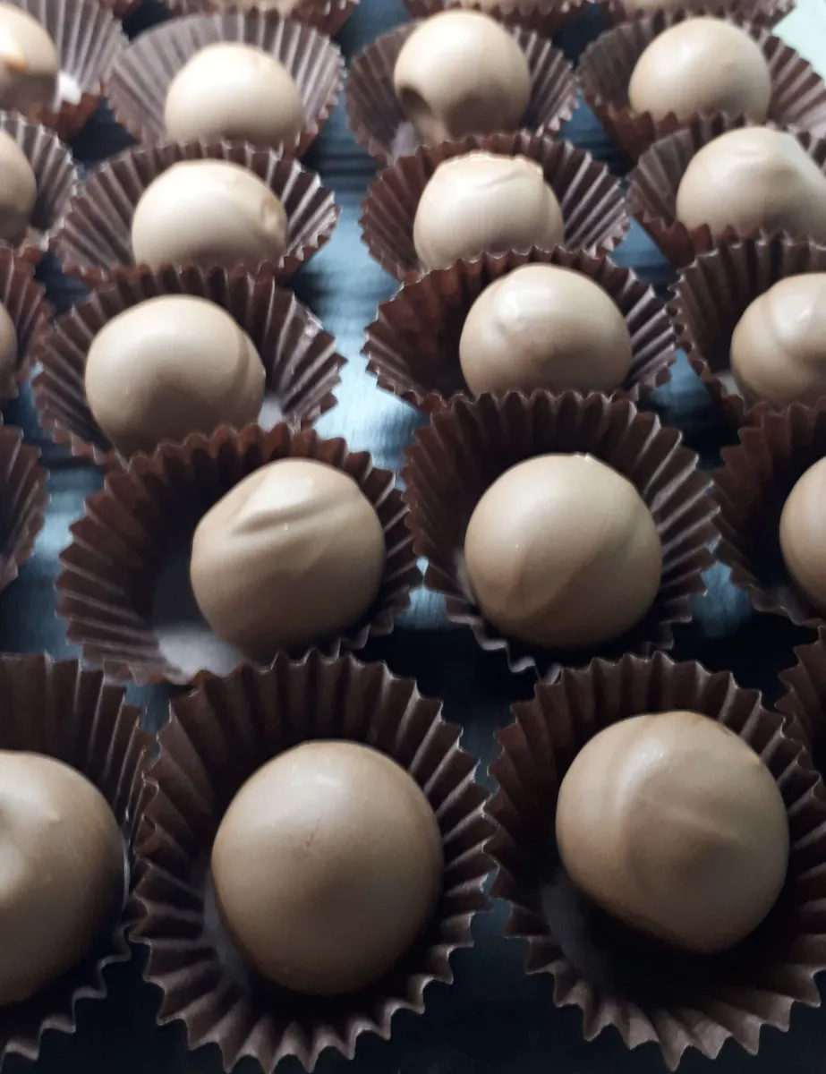 Rows of chocolate truffles in brown paper cups.
