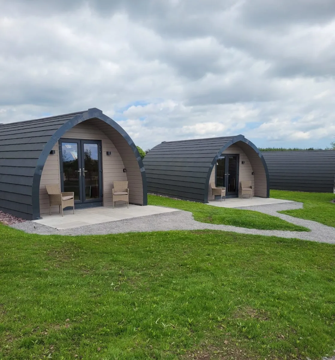 Two modern glamping pods with chairs outside