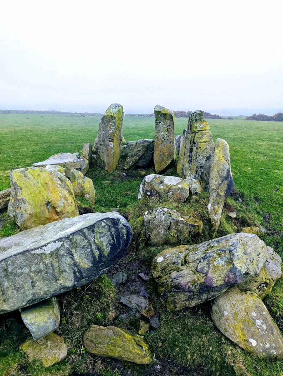 Ancient stone circle on grassy field.