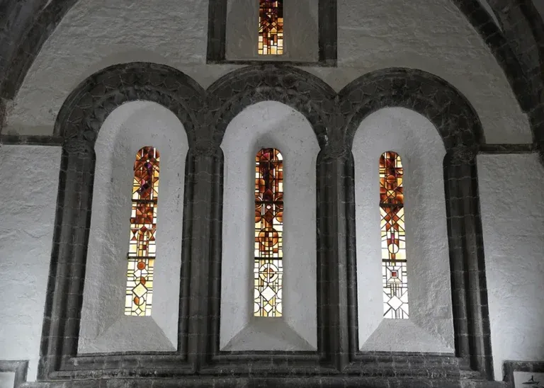 Stained glass windows in an arched stone wall.