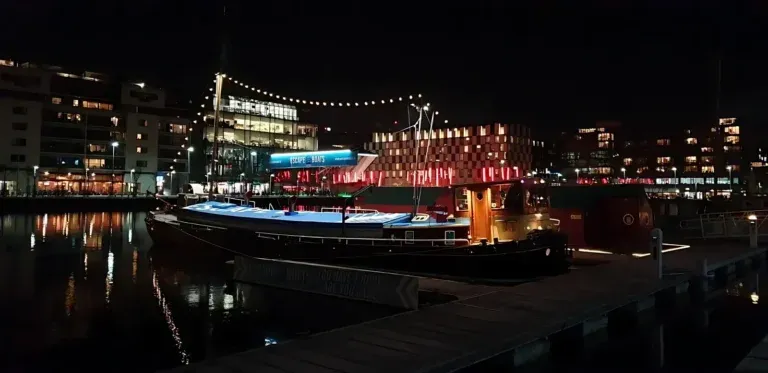 Boat docked at night with city lights