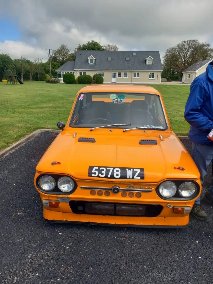 Orange vintage car parked in front of a house.