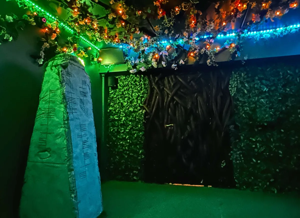 Dimly lit room with stone pillar and colorful lights.