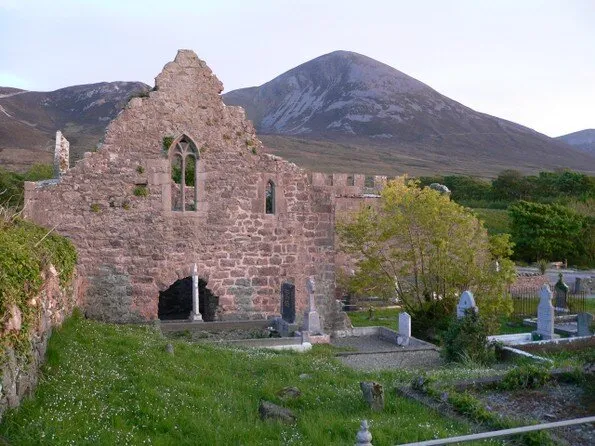 Ruins of a stone building with a mountain in the background.