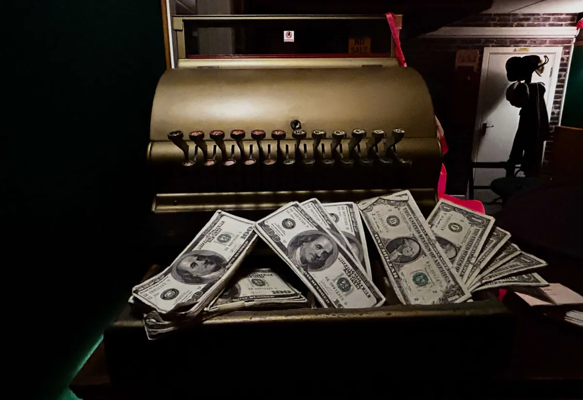 Old cash register with dollar bills.