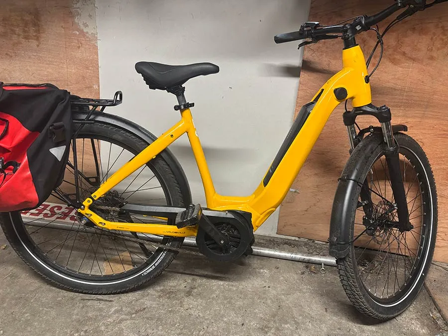 Yellow electric bicycle with red pannier bag