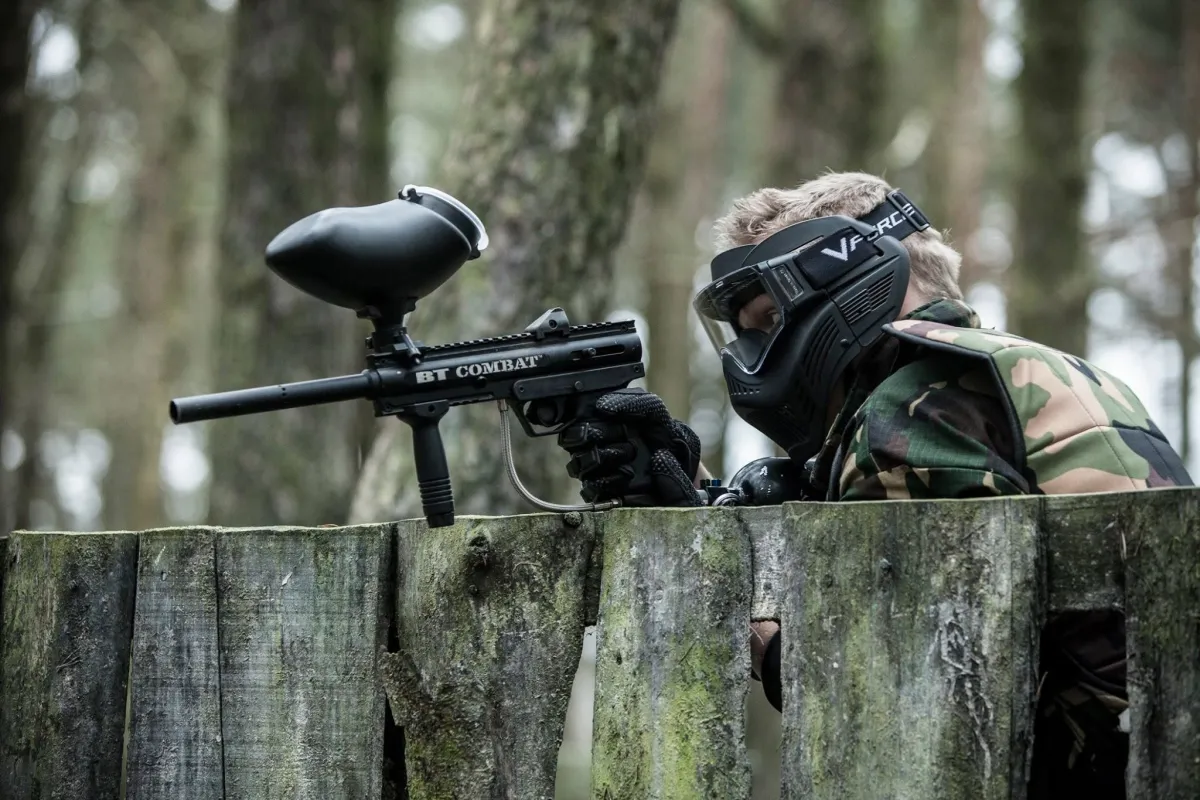 Person in camouflage playing paintball in forest.