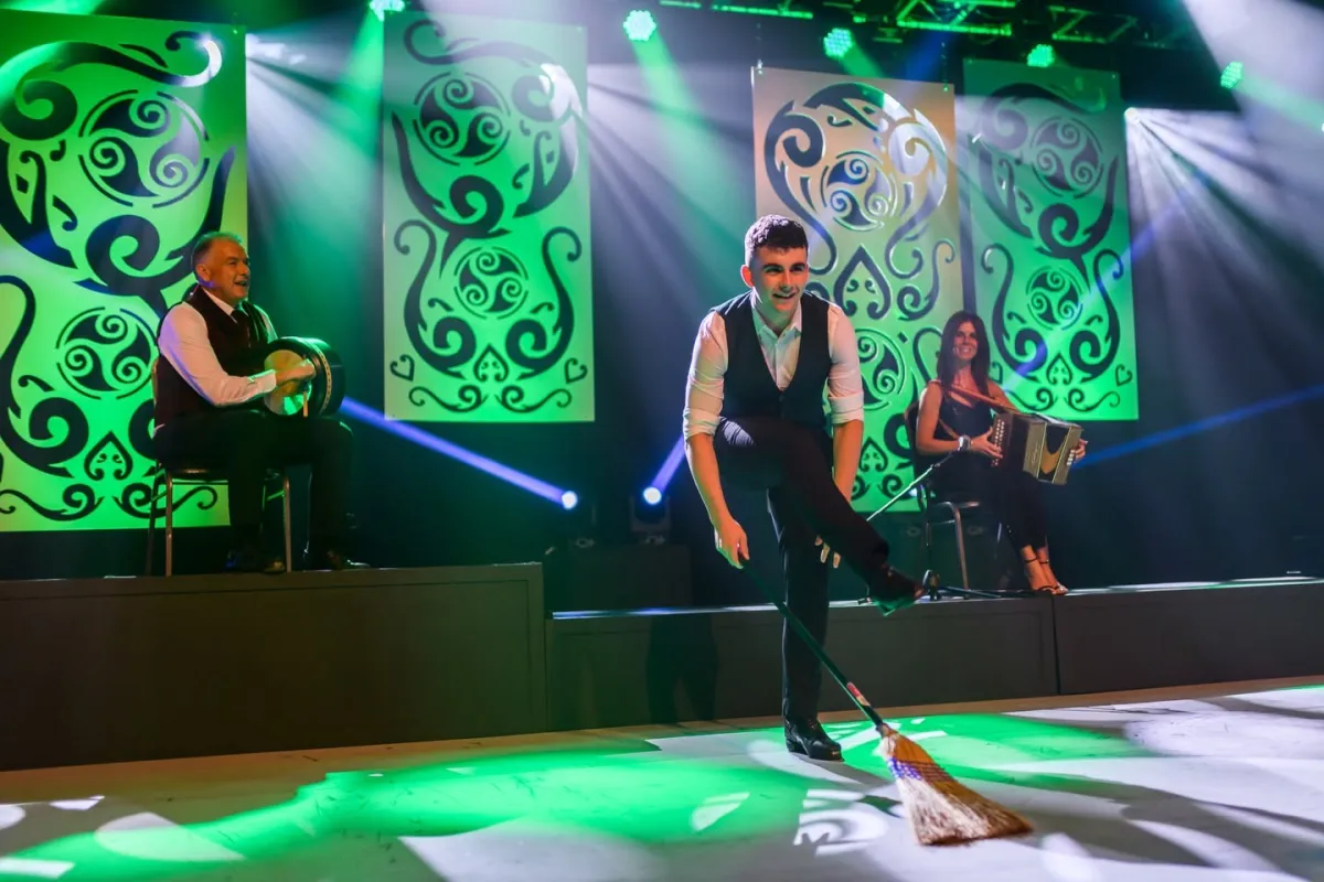 Performers on stage with green decorative panels.