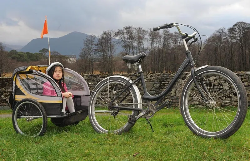 Child in a bike trailer next to a bicycle