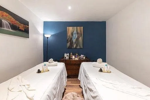 Two massage tables in a spa room with art on walls.