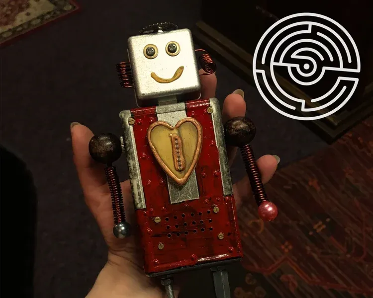 Hand holding a small robot with a heart design.