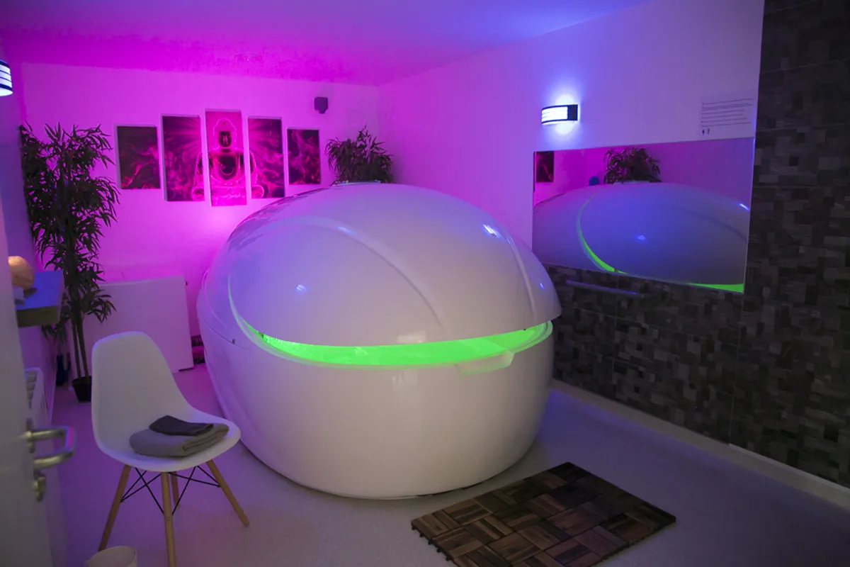 Floatation tank in a dimly lit room with purple lighting.