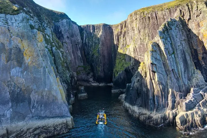 Small boat navigating between tall rocky cliffs