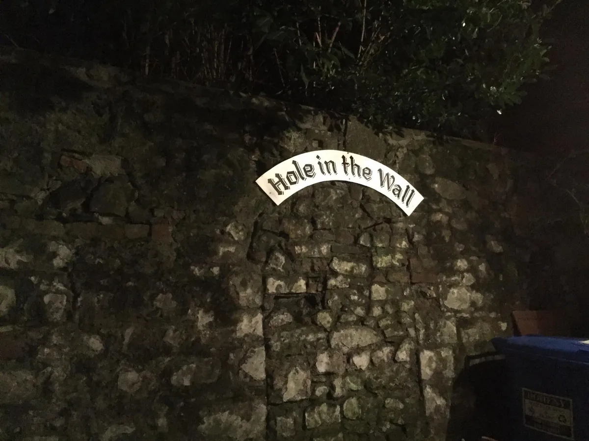 Stone wall with 'Hole in the Wall' sign.