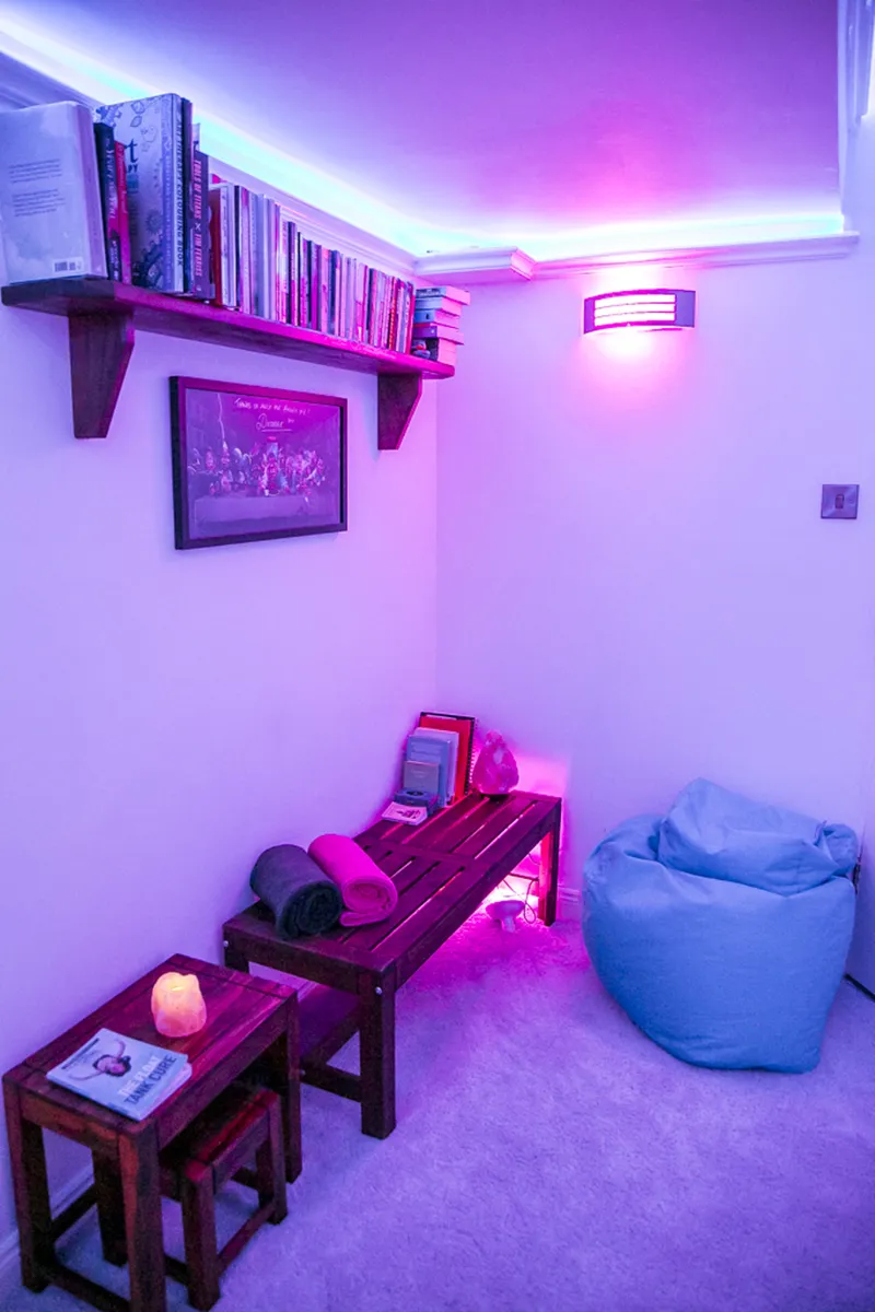 Cozy room with purple lighting, books, and a bean bag.